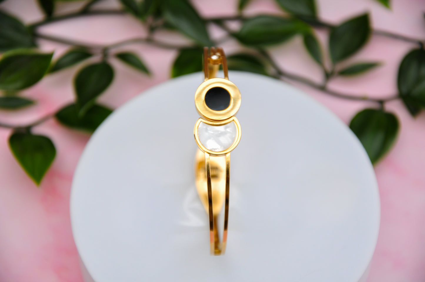 Gold bangle bracelet with black and white circular accents, stylish and modern jewelry piece.