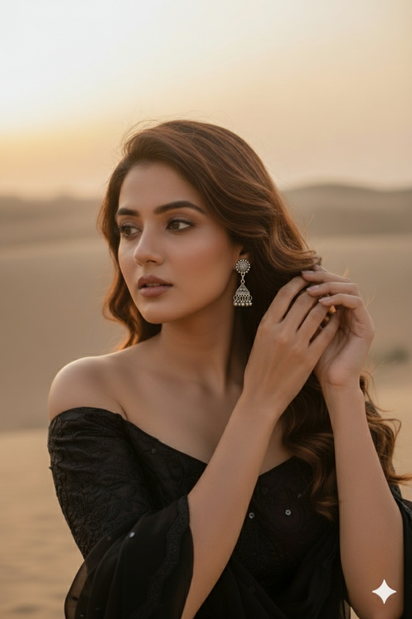 Elegant silver chandelier earrings worn with a black off-shoulder dress in a desert sunset backdrop.