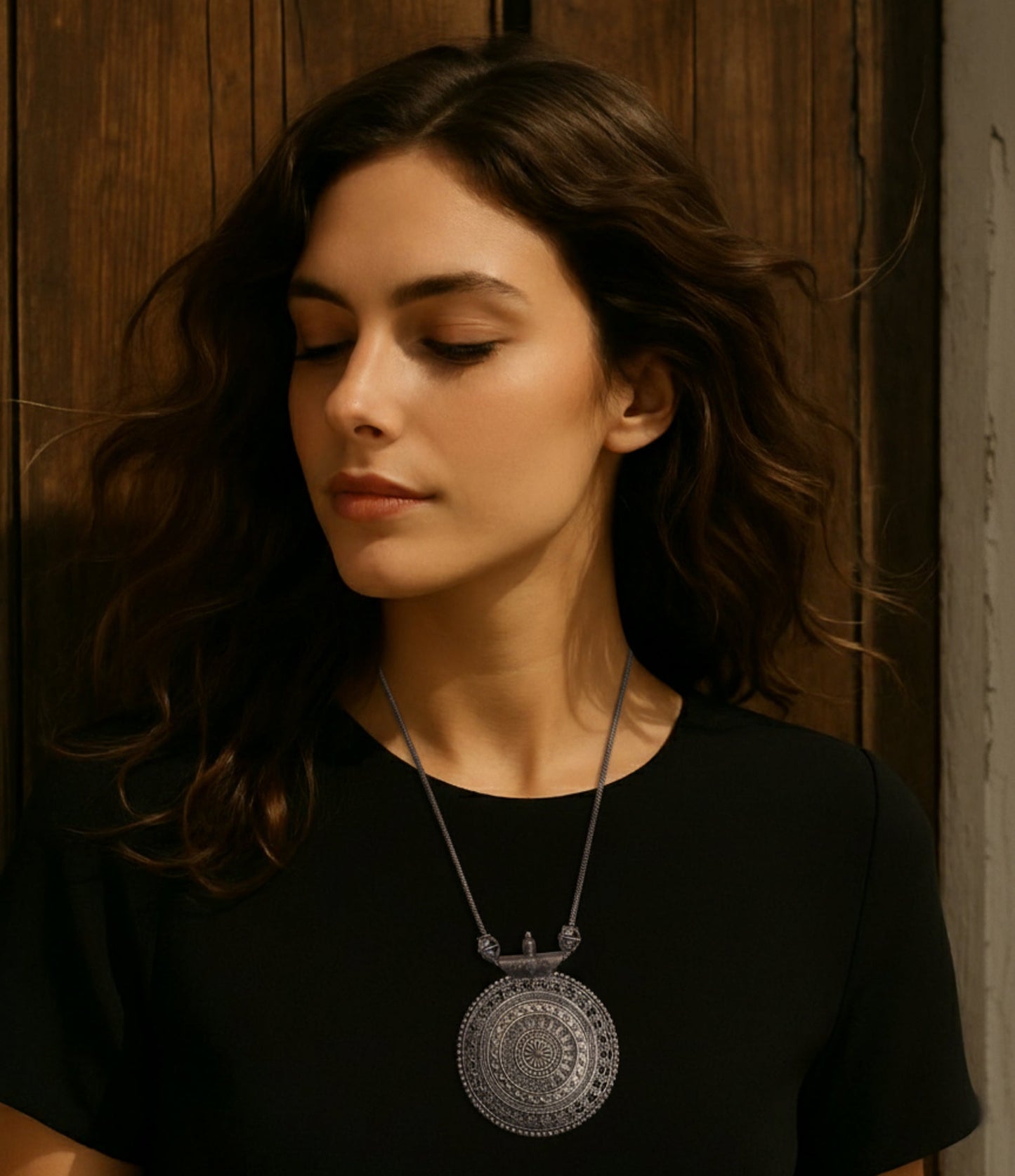 Elegant silver pendant necklace featuring intricate mandala design, worn by a model on a black top.