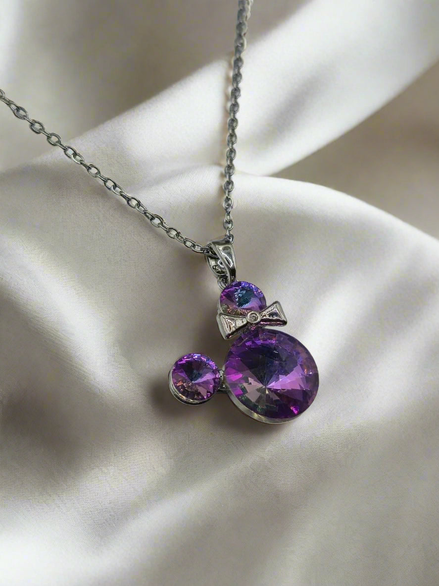Elegant purple gemstone necklace with silver chain and bow tie pendant.