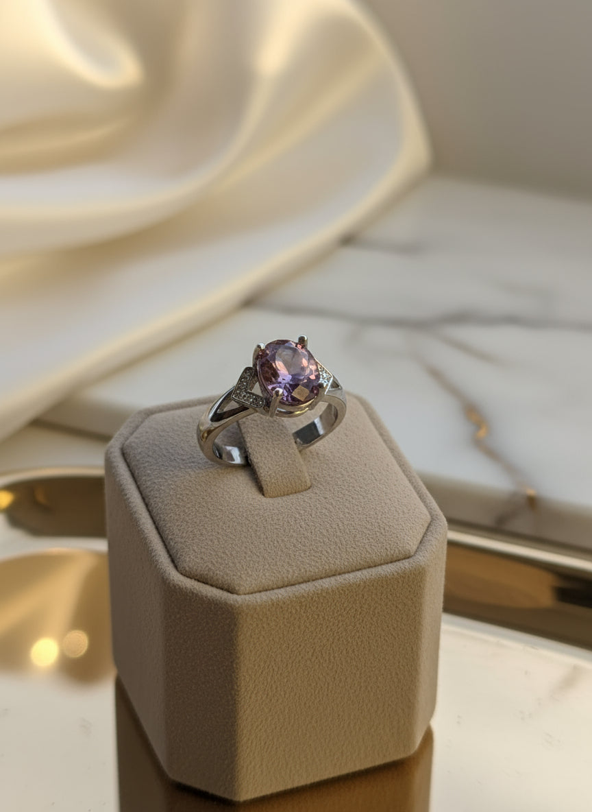 Handcrafted silver ring featuring an oval purple gemstone, displayed on a soft velvet ring box.