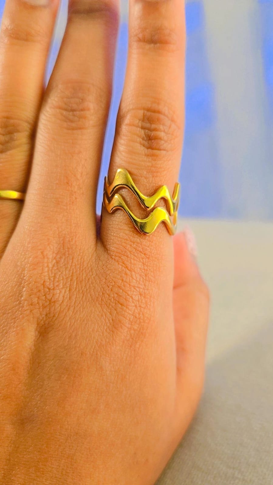 Gold wave ring made of metal, showcasing a stylish, wavy design on a finger.