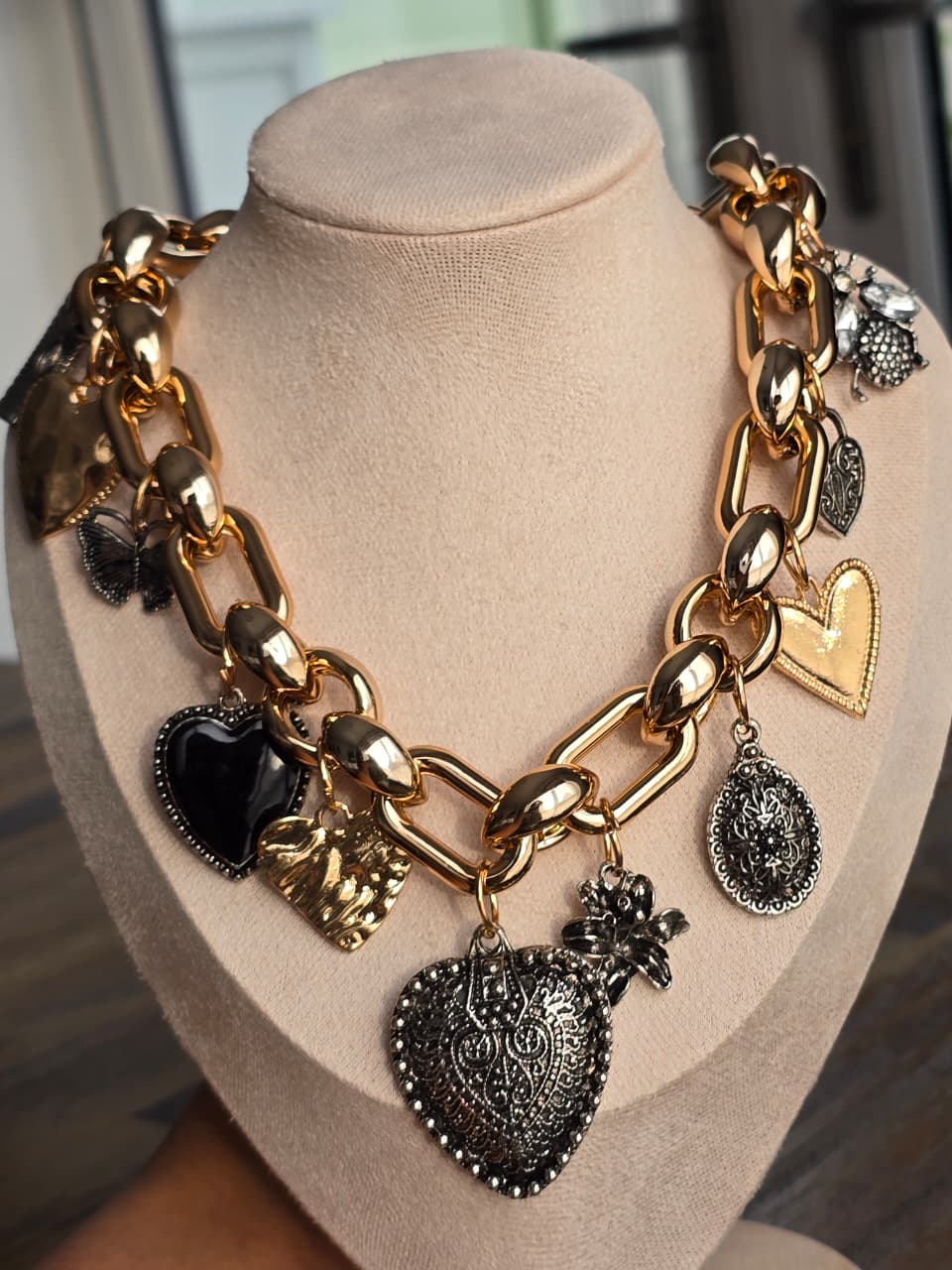 Gold statement necklace with mixed heart charms and decorative accents, trendy accessory for stylish outfits.