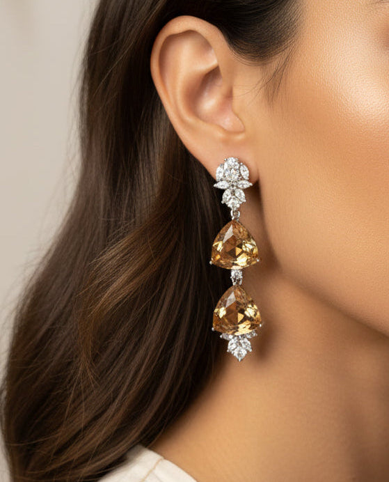 Elegant gold and crystal drop earrings featuring a geometric design and sparkling embellishments.