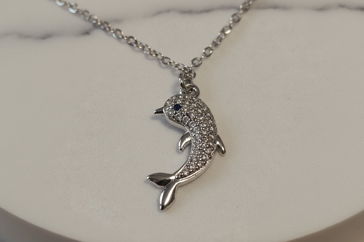 Silver dolphin pendant necklace with sparkling crystals and a blue gemstone eye.