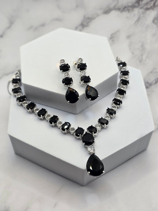 Elegant black gemstone necklace and earrings set in silver metal, featuring teardrop and round stones.