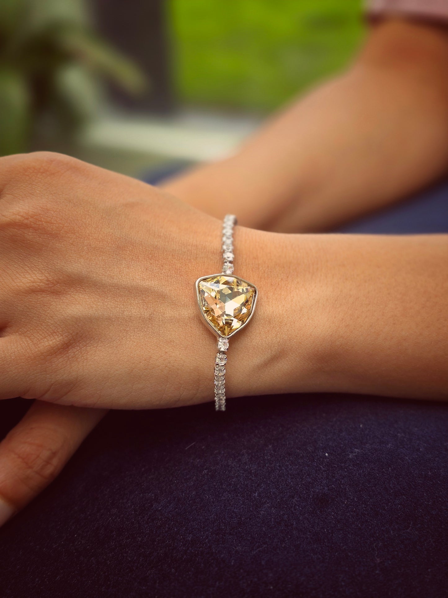 Elegant gold bracelet featuring a large yellow gemstone and sparkling silver chain detail.