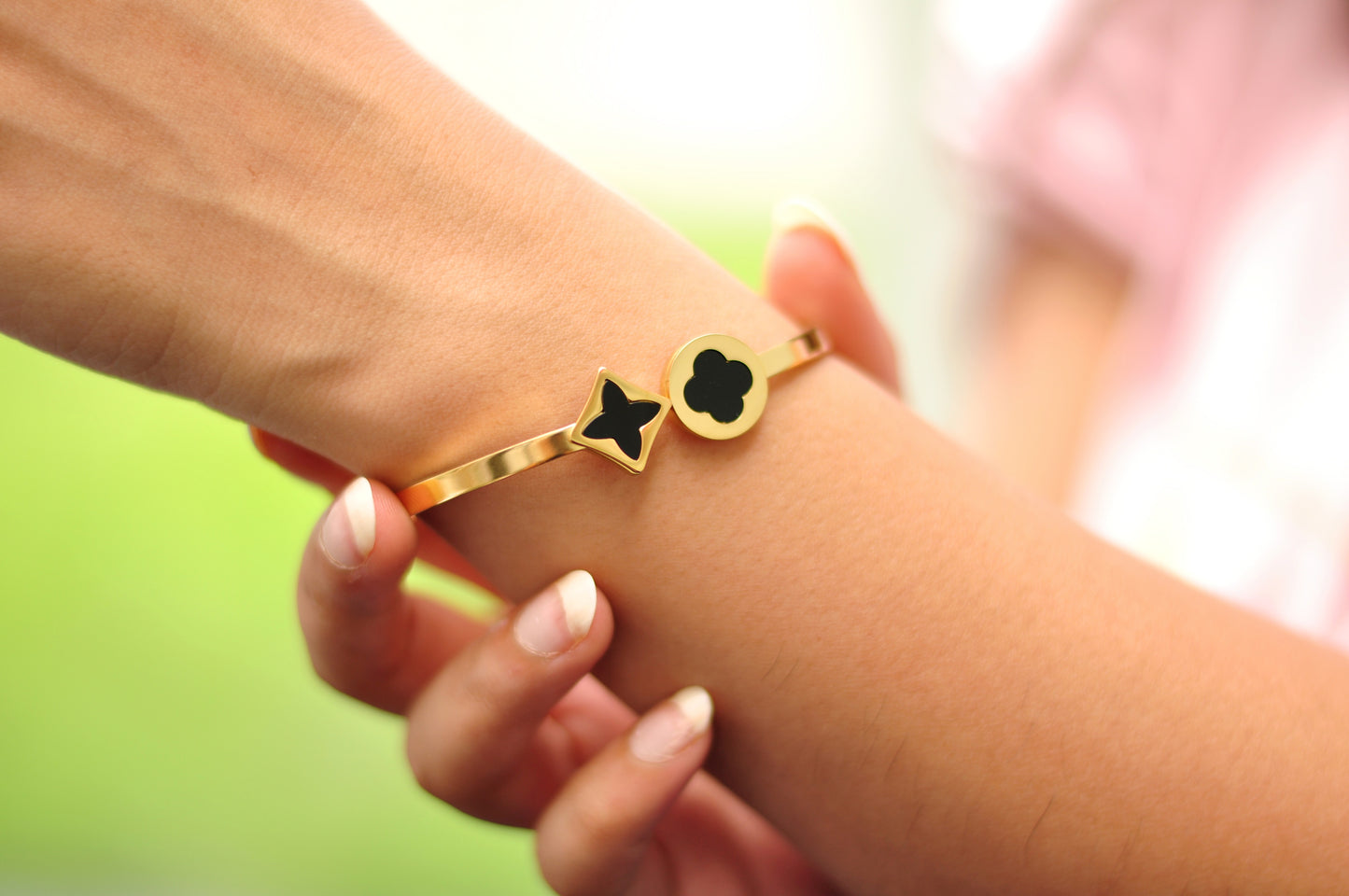 Gold bracelet with black star and flower charms, stylish accessory for everyday wear.
