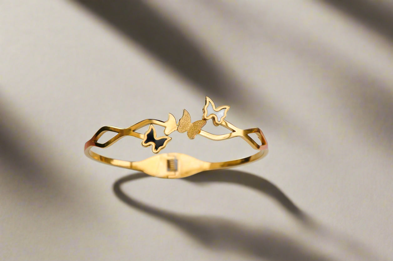 Elegant gold butterfly bracelet with intricate design and enamel accents.
