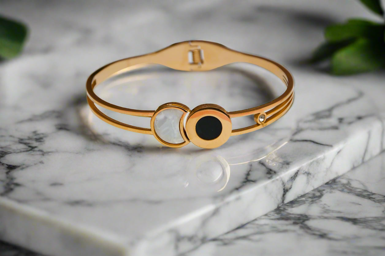 Elegant gold bangle bracelet with black and white stones, perfect for stylish everyday wear.