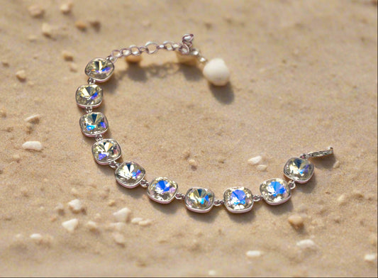 Elegant silver bracelet with sparkling colorful crystals on a sandy background.