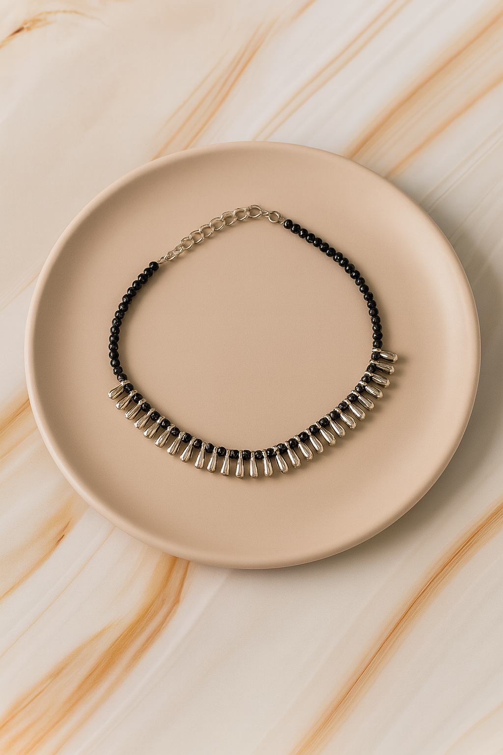 Elegant black beaded necklace with silver accents on a beige plate, perfect for any occasion.