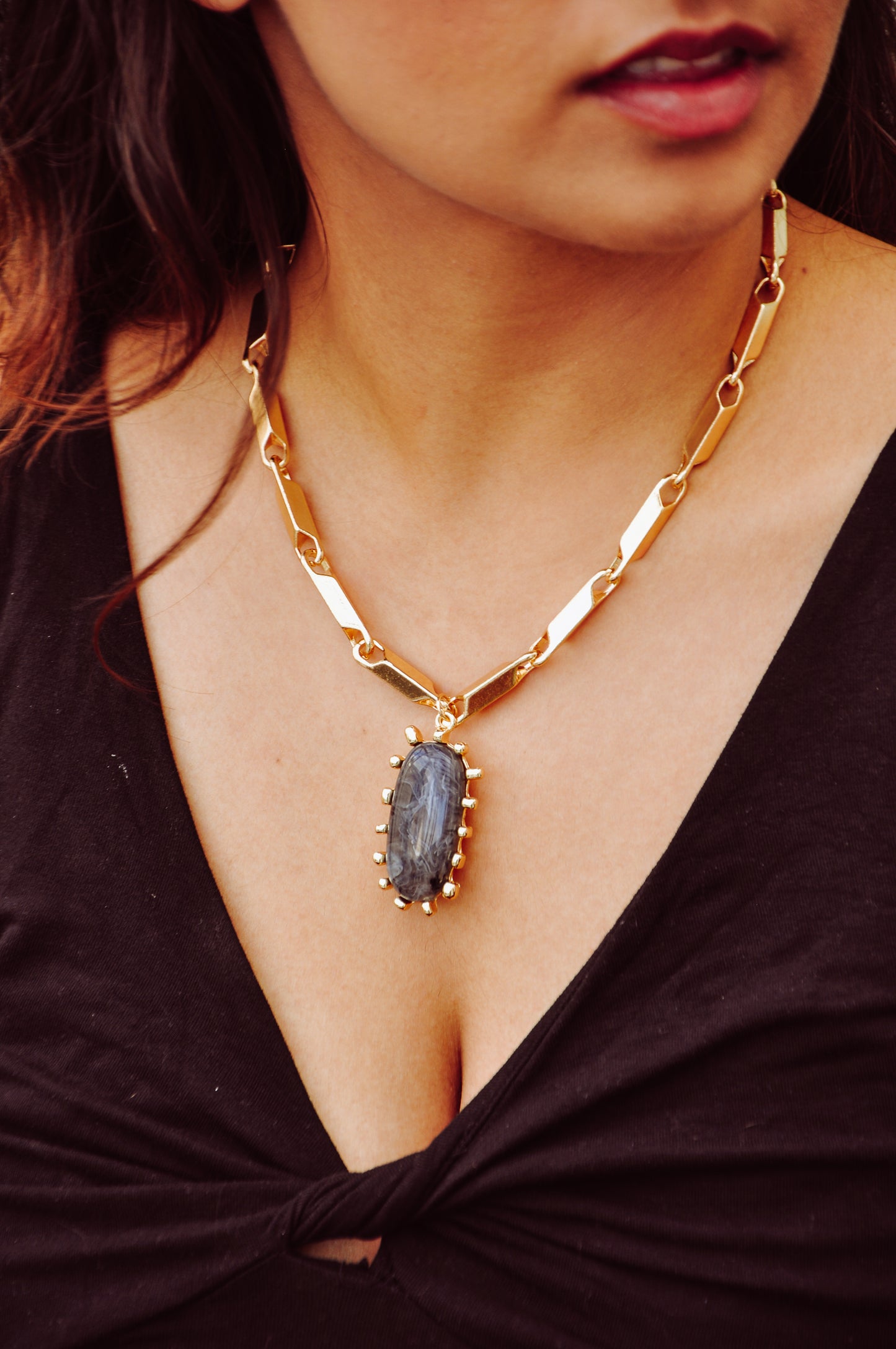 Gold chain necklace featuring a large blue stone pendant, perfect for adding elegance to any outfit.