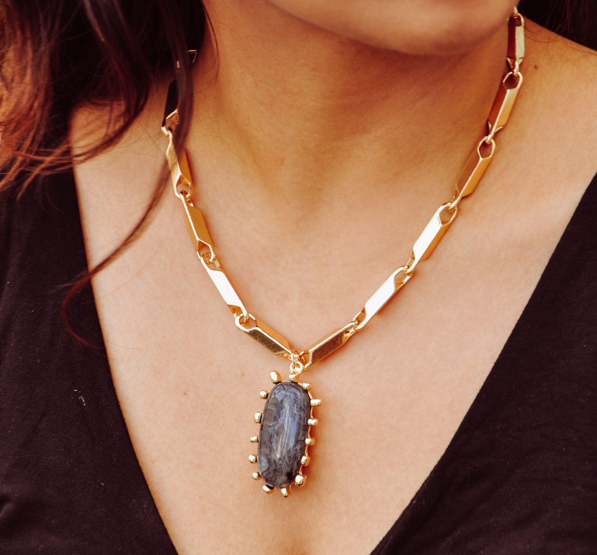 Gold chain necklace featuring a large oval black stone with spikes, perfect for stylish occasions.