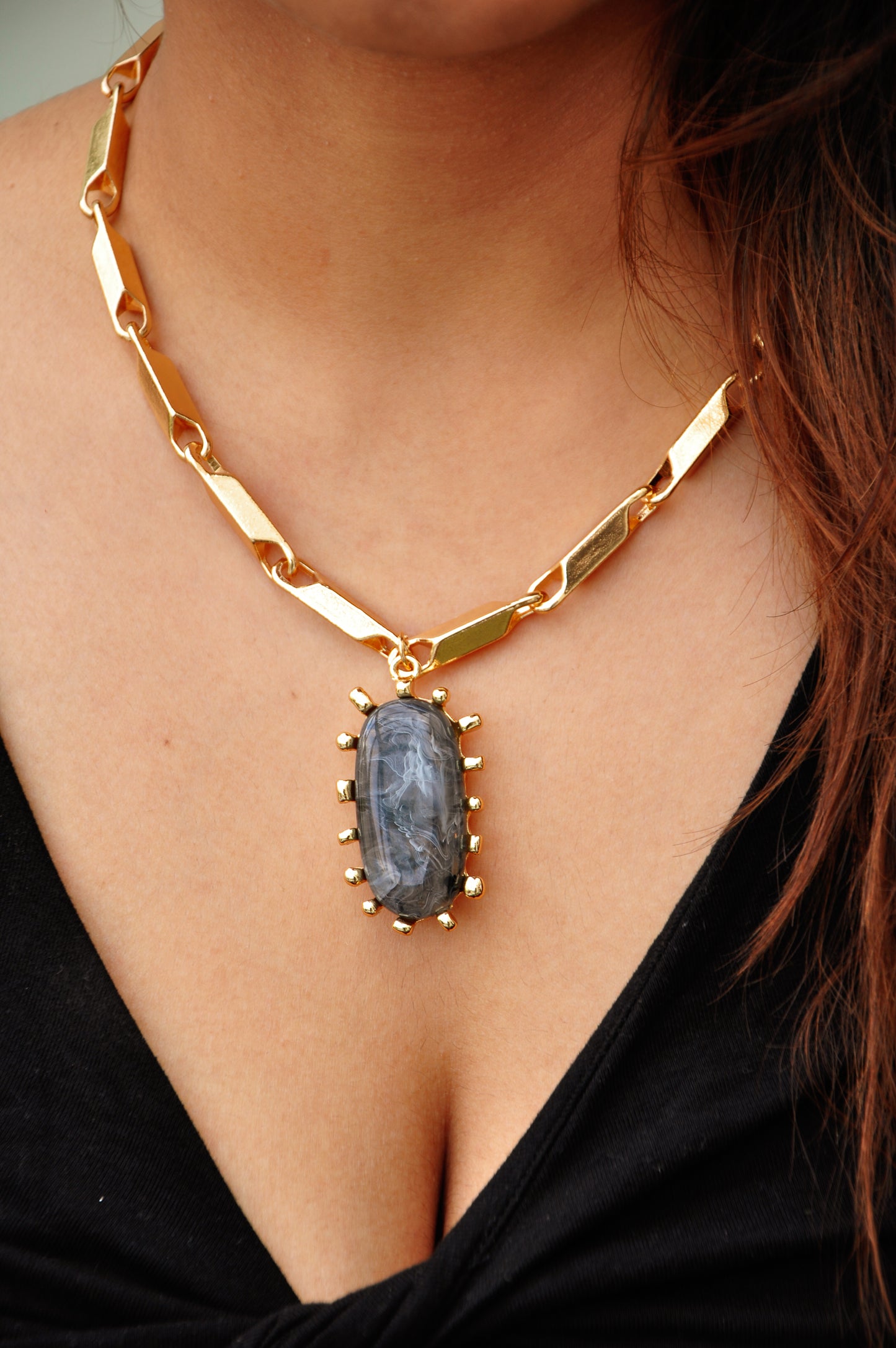 Gold chain necklace with a large gray stone pendant, perfect for bold fashion statements.
