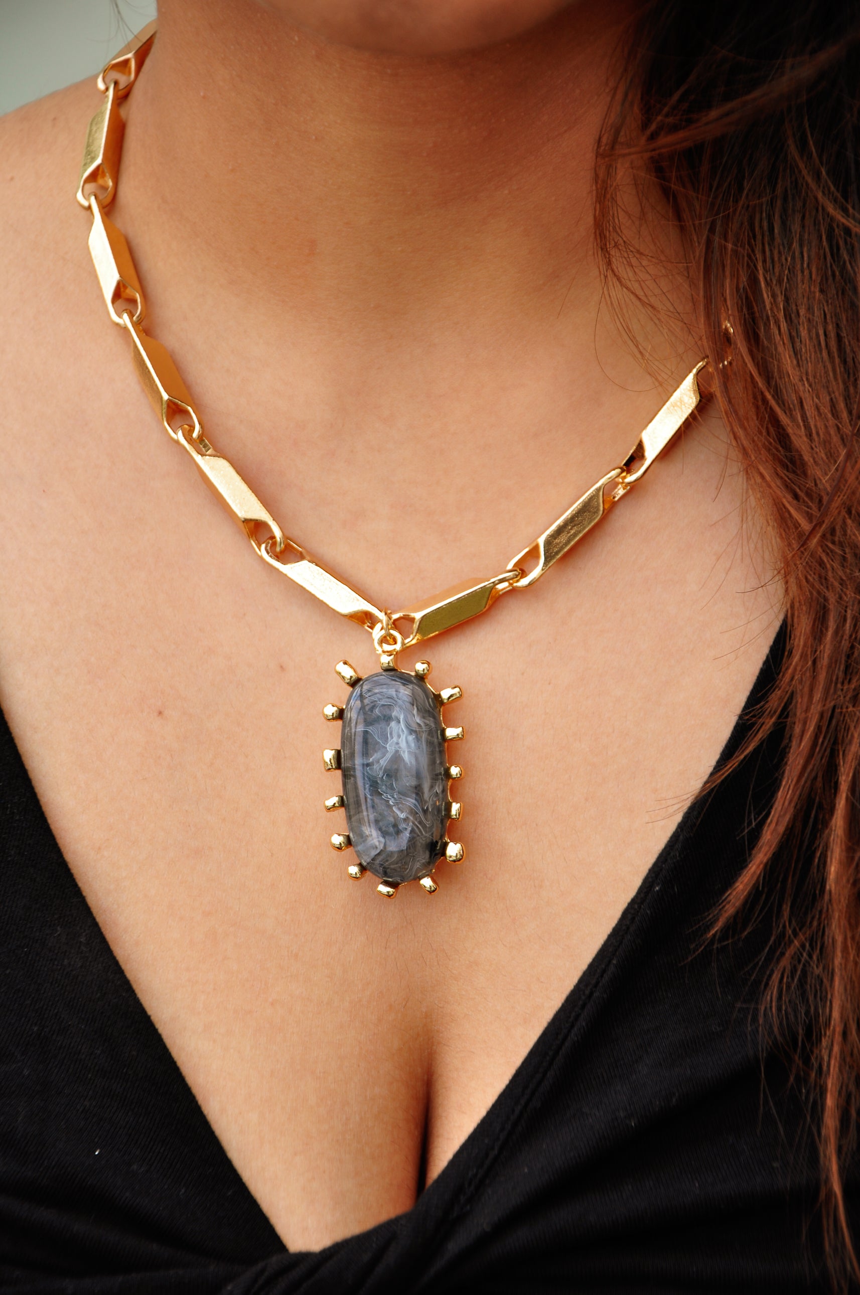 Gold chain necklace with a large gray stone pendant, perfect for bold fashion statements.