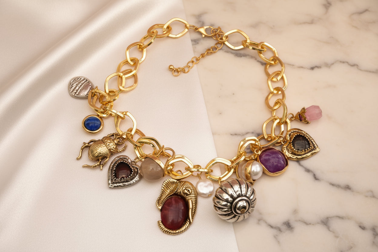Gold charm necklace featuring assorted gemstones and intricate pendants on a delicate chain.