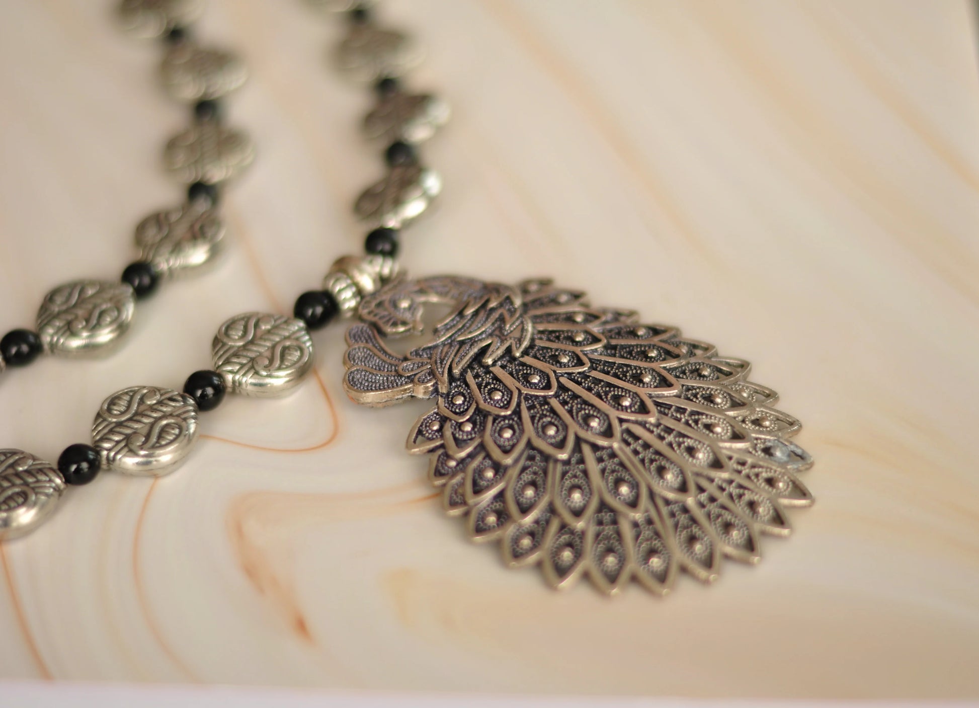 Silver pendant necklace with ornate design and black beads, perfect for bohemian style.