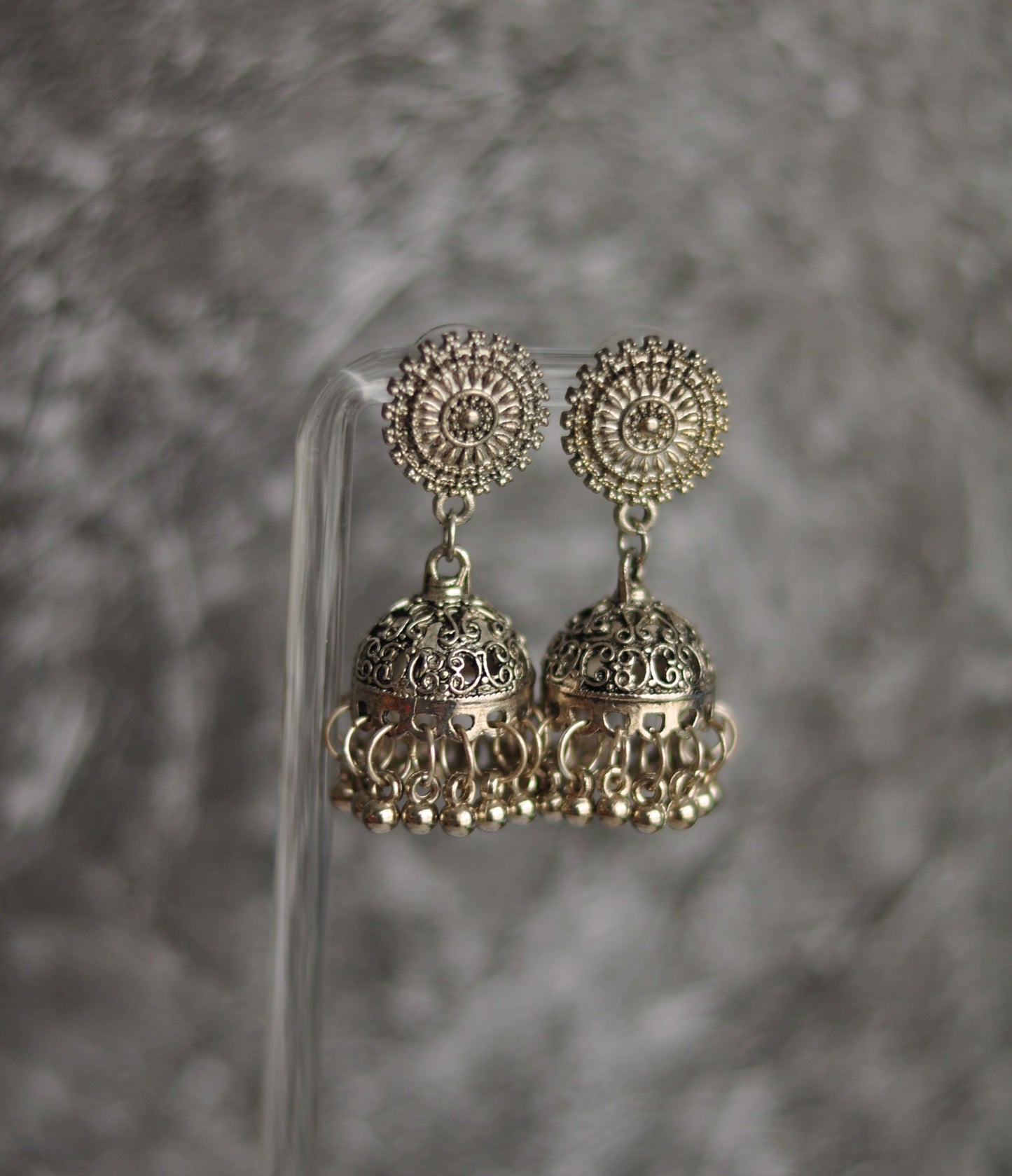 Silver jhumka earrings with intricate design and floral pattern, perfect for traditional attire.