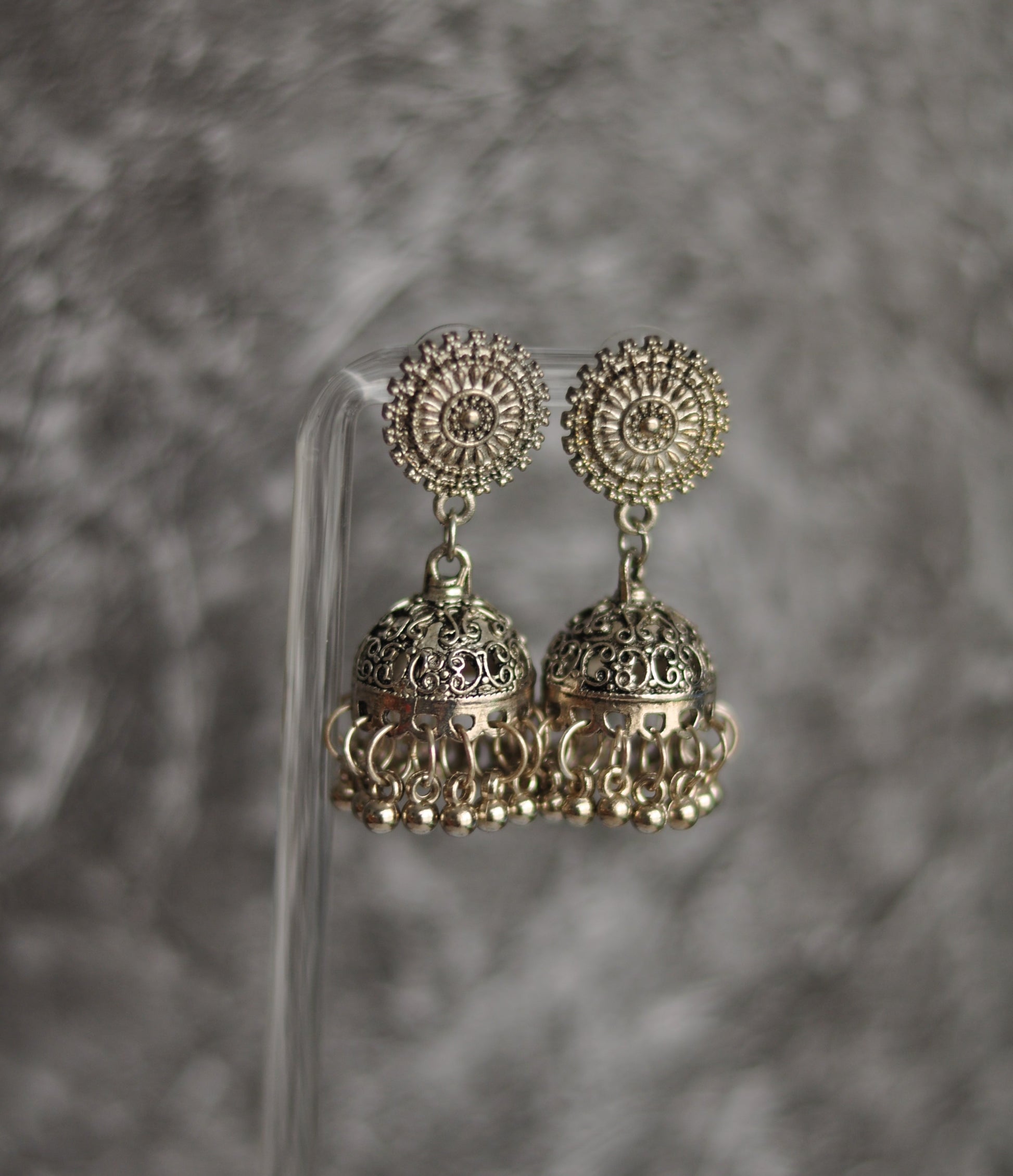Silver jhumka earrings with intricate design and floral pattern, perfect for traditional attire.