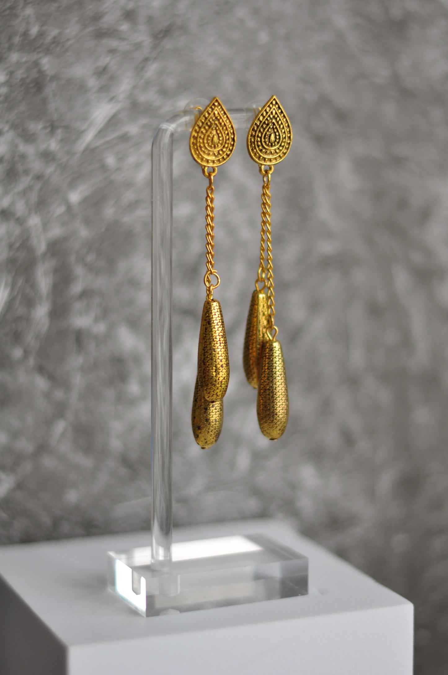 Elegant gold drop earrings with leaf-shaped tops and textured pendants for a stylish look.