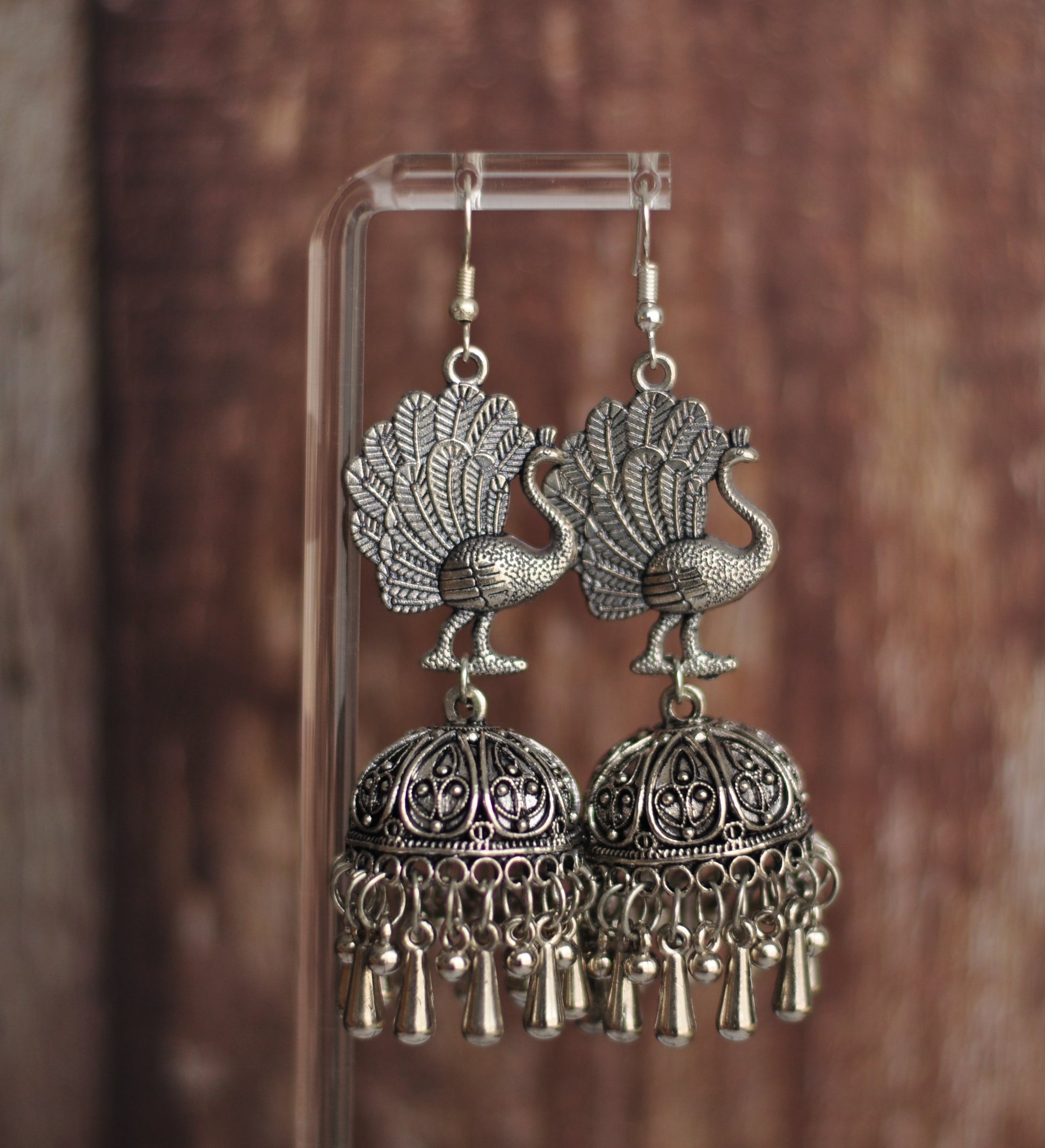 Traditional silver peacock earrings with intricate design and hanging tassels, perfect for festive occasions.