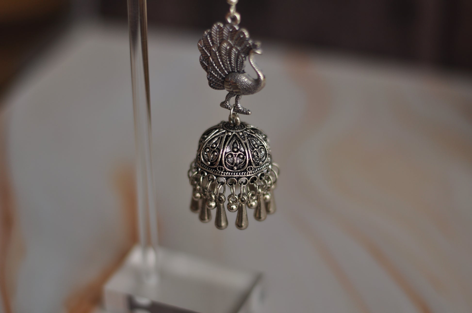 Silver peacock pendant with intricate detailing and dangling beads, ideal for boho jewelry style.