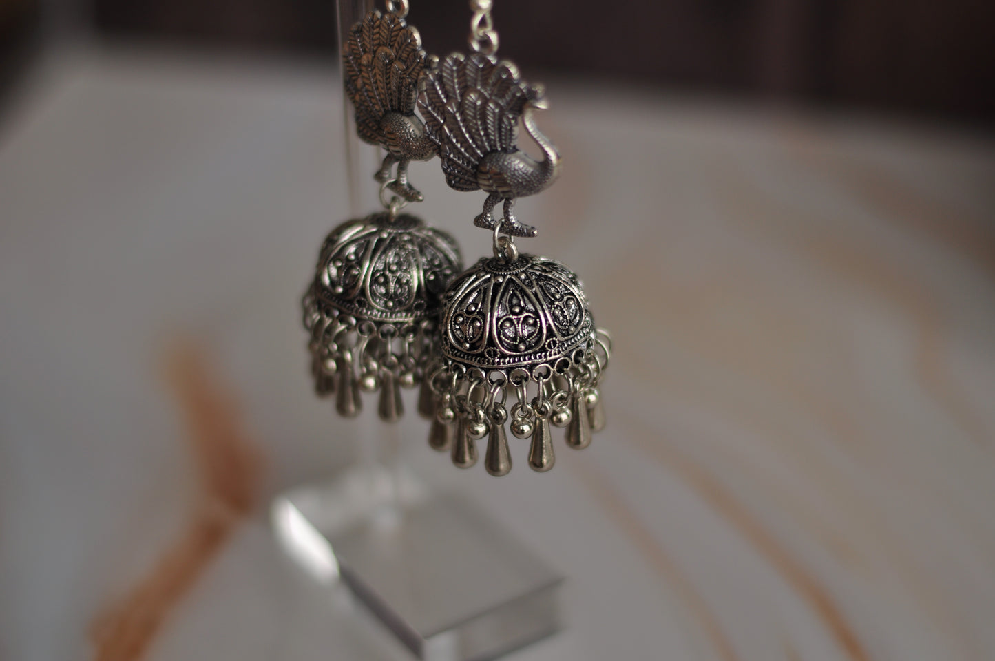 Elegant silver peacock earrings with intricate designs and dangling charms, perfect for stylish outfits.