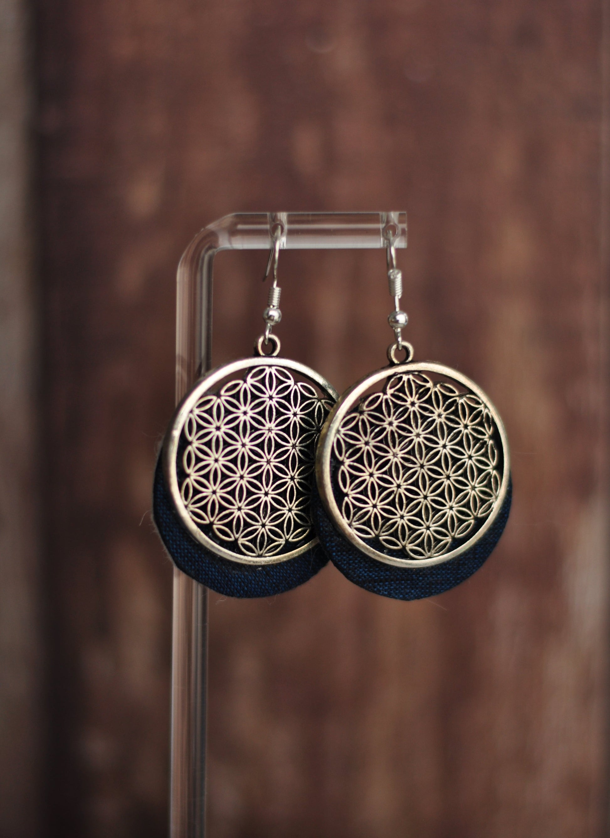 Flower-shaped dangling earrings in gold and navy with intricate cut-out design.