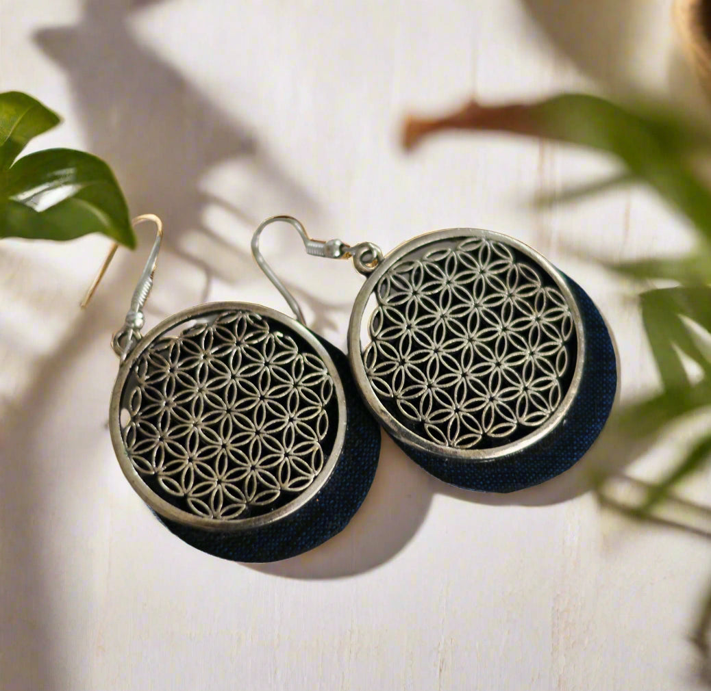 Silver flower pattern earrings with dark blue fabric backing, elegant and stylish accessory.