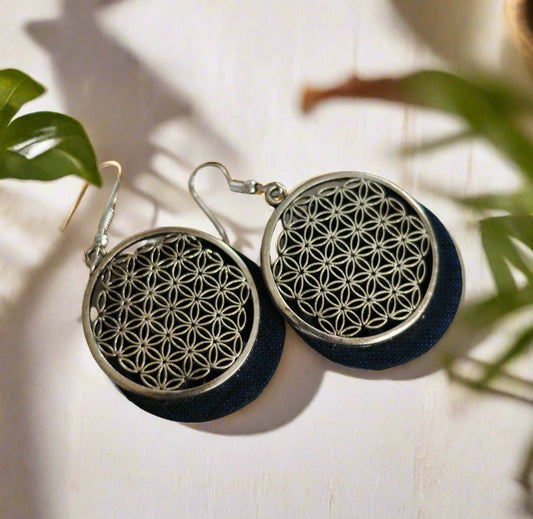 Silver flower pattern earrings with dark blue fabric backing, elegant and stylish accessory.