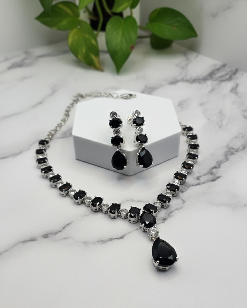 Elegant black gemstone necklace and earrings set in silver setting, perfect for formal occasions.