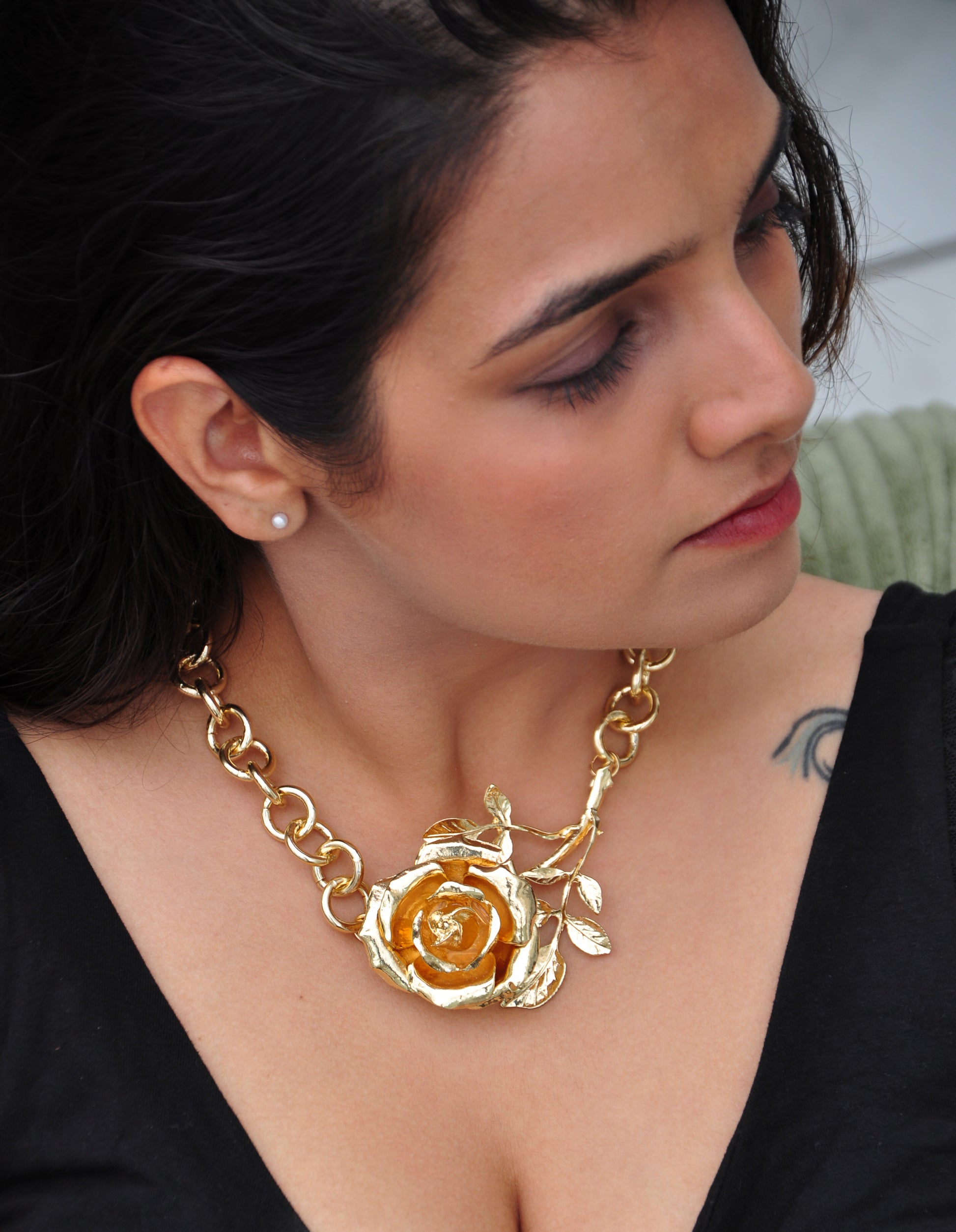 Gold floral statement necklace with rose pendant and chain design, perfect for elegant occasions.