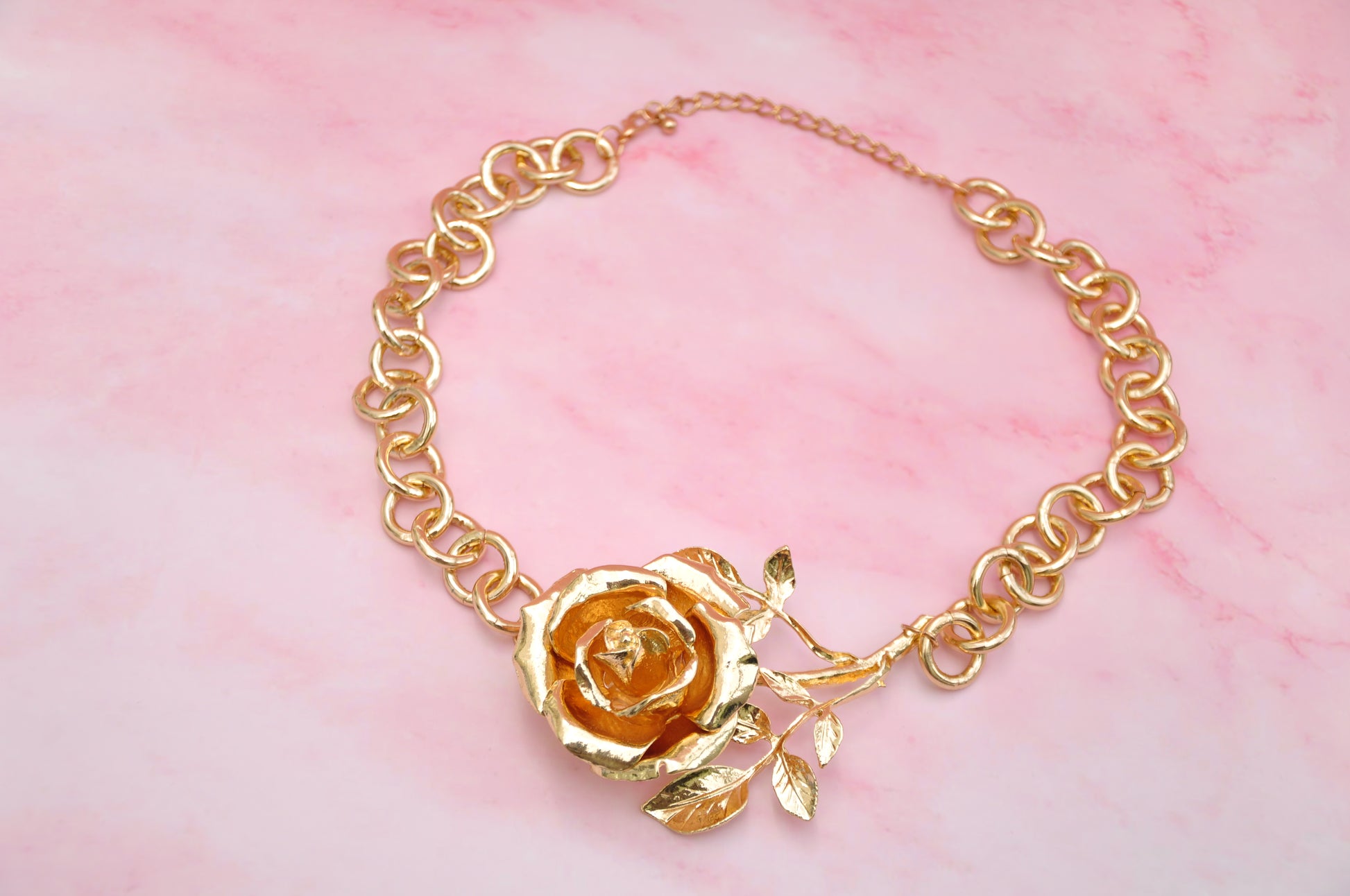 Gold floral statement necklace featuring a rose design and chain link, perfect for elegant styling.