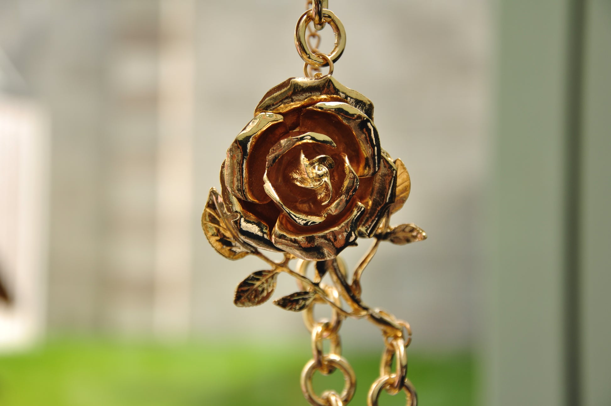 Gold rose pendant necklace with intricate detailing and chain, perfect for elegant occasions.