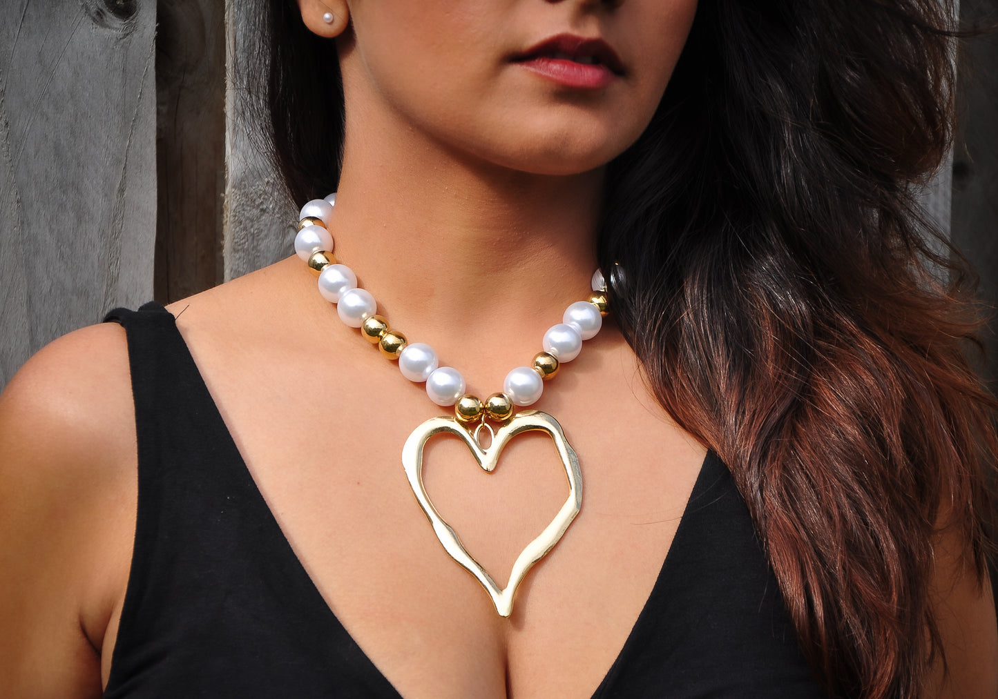 Stylish heart-shaped gold pendant necklace with white pearls and golden beads, perfect for elegant outfits.