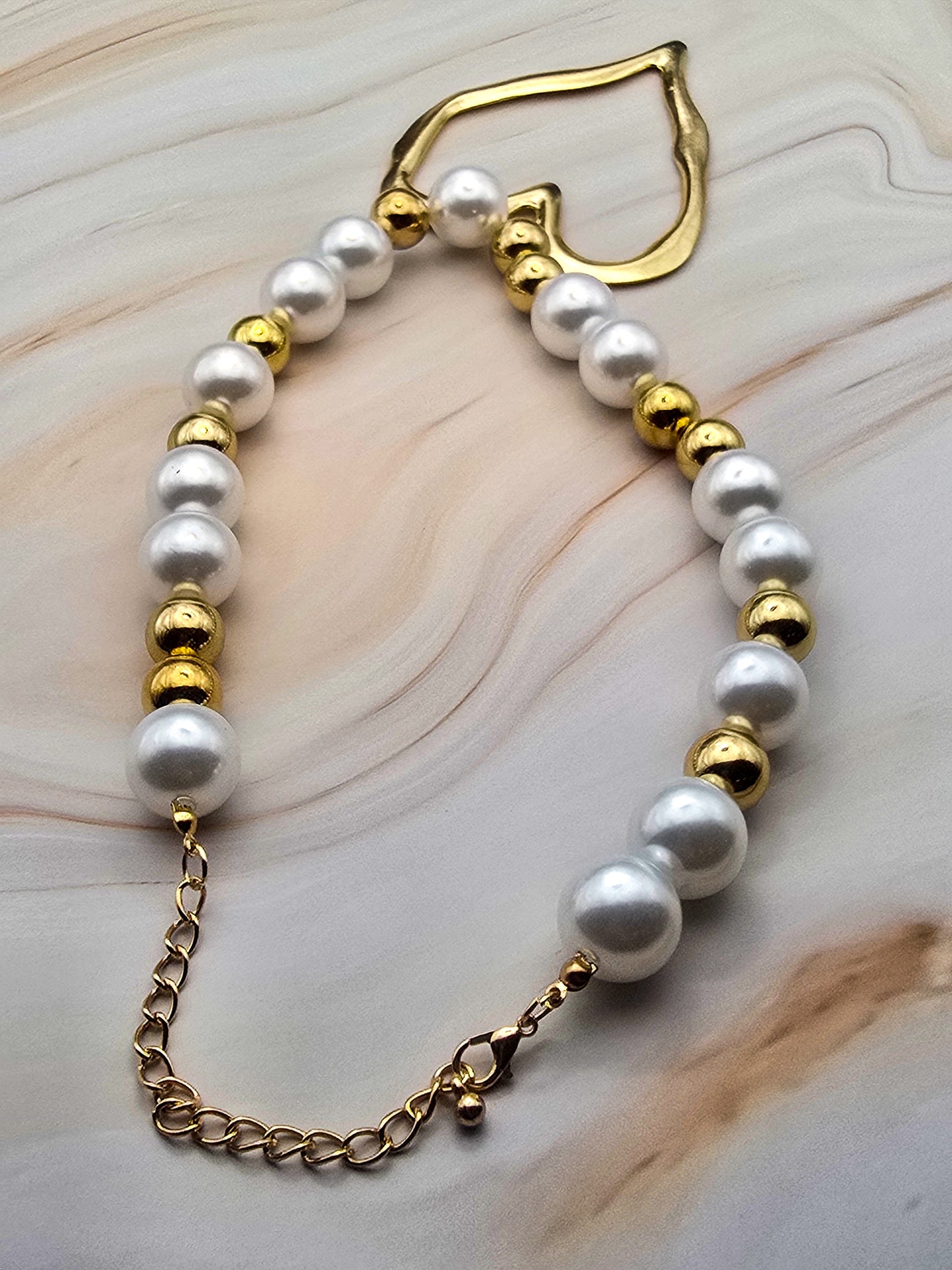 Gold and white pearl bracelet featuring a golden heart clasp and adjustable chain.