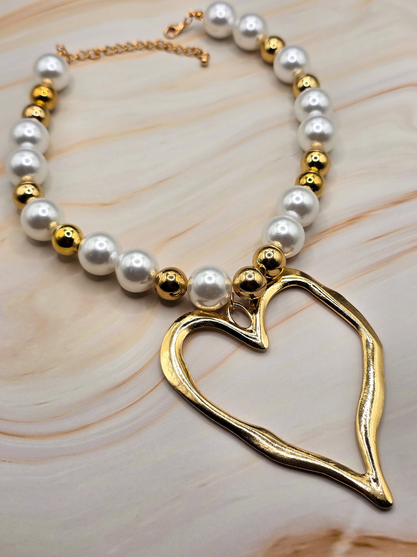 Gold heart pendant necklace with pearl and gold bead accents, elegant jewelry for any occasion.