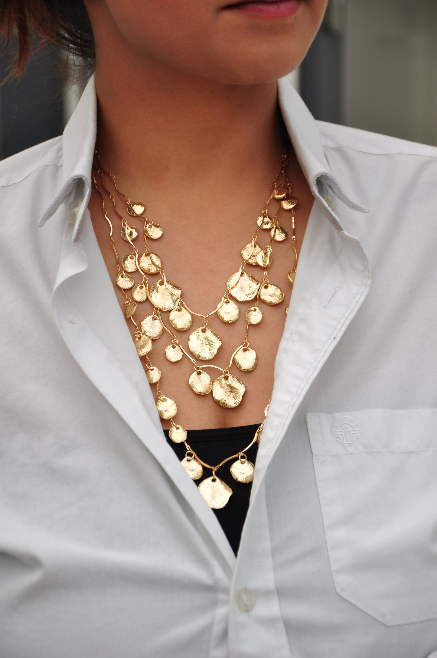 Elegant gold layered necklace featuring textured leaf-shaped pendants, perfect for a stylish look.