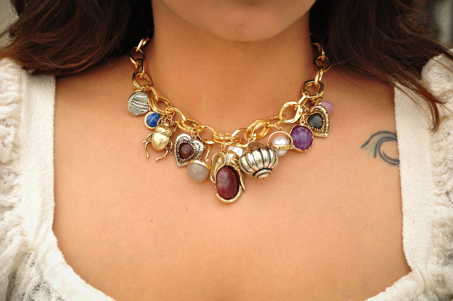 Gold charm necklace with colorful stones and intricate designs, perfect for adding a unique touch to outfits.