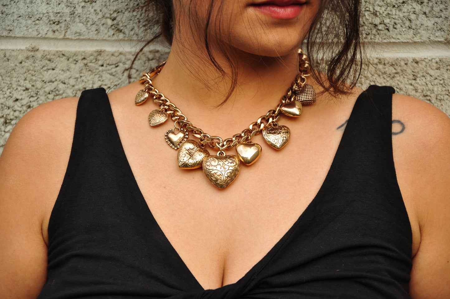 Bold gold heart charm necklace with intricate designs, perfect for adding elegance to any outfit.