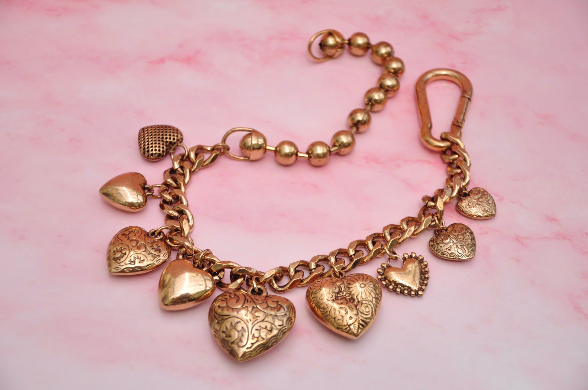 Gold heart charm bracelet with intricate designs and clasp, perfect for stylish accessories.