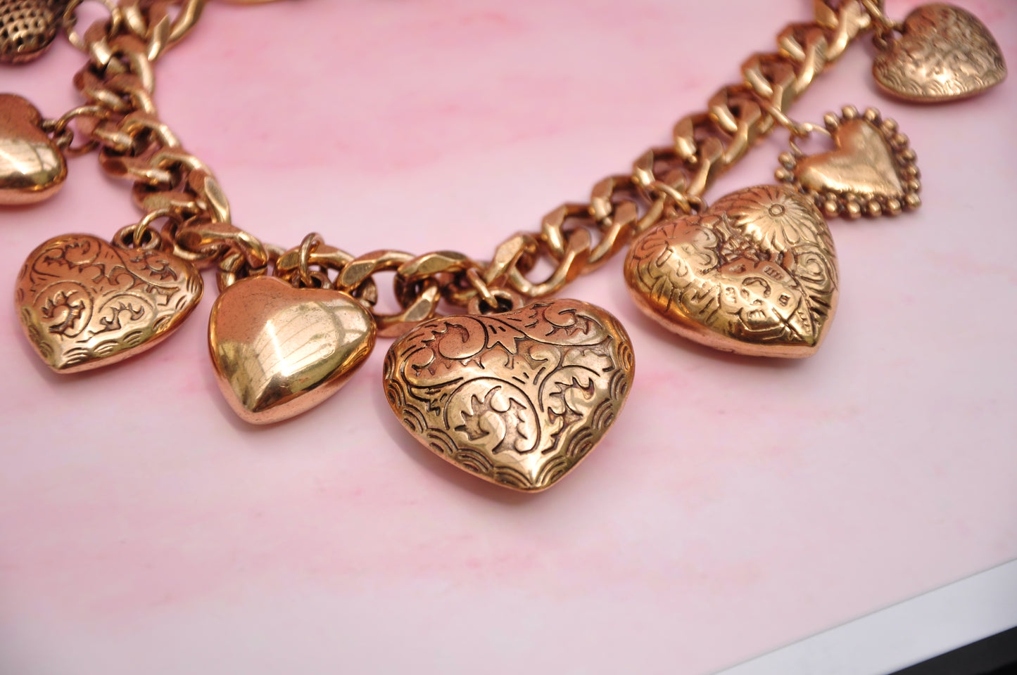 Gold heart charm bracelet with ornate designs, perfect for adding elegance to any outfit.