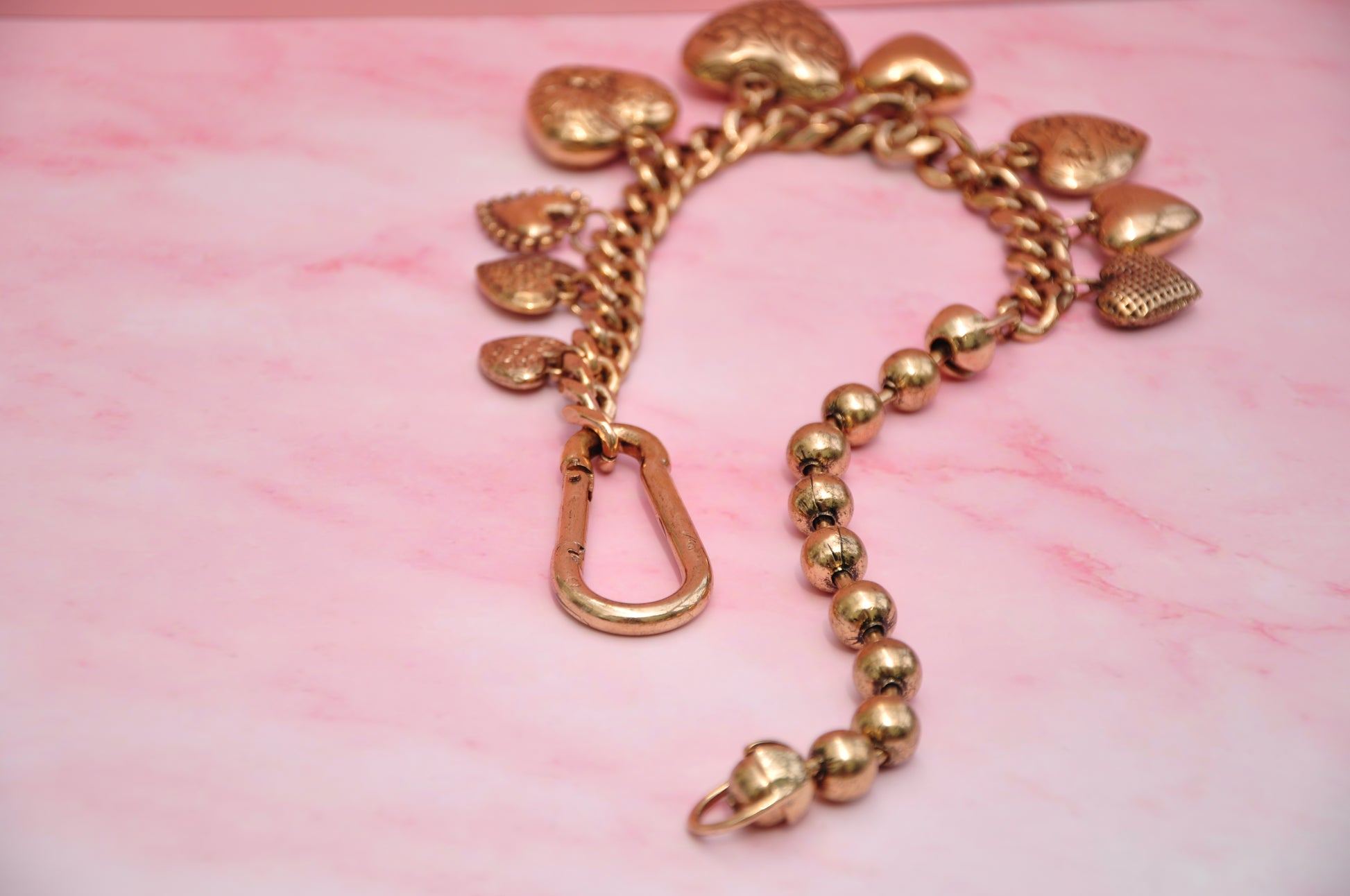 Gold heart charm bracelet with a chunky chain and beads, perfect for adding a stylish touch to any outfit.