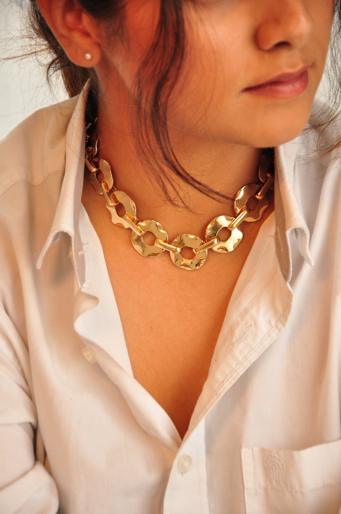 Stylish gold statement necklace made of hammered metal links for a chic look.