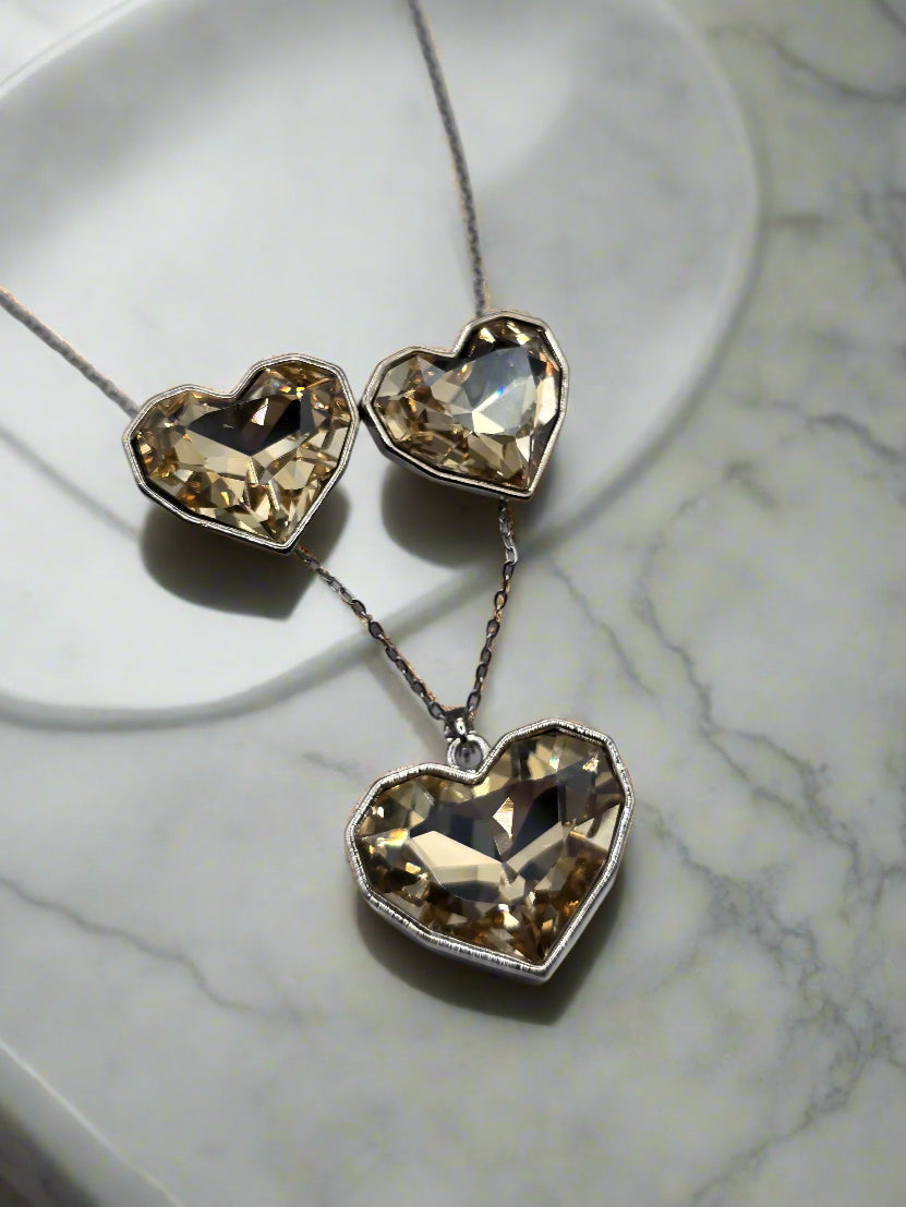 Elegant heart-shaped necklace and earrings set with sparkling champagne-colored crystals, silver chain.