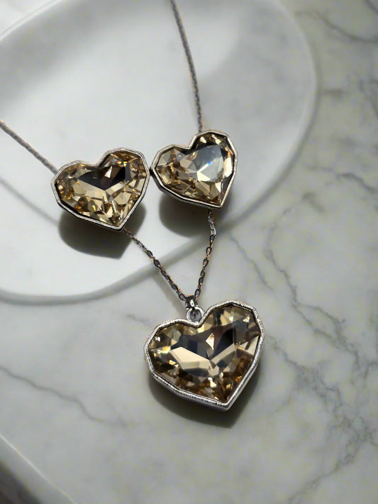 Elegant heart-shaped necklace and earrings set with sparkling champagne-colored crystals, silver chain.