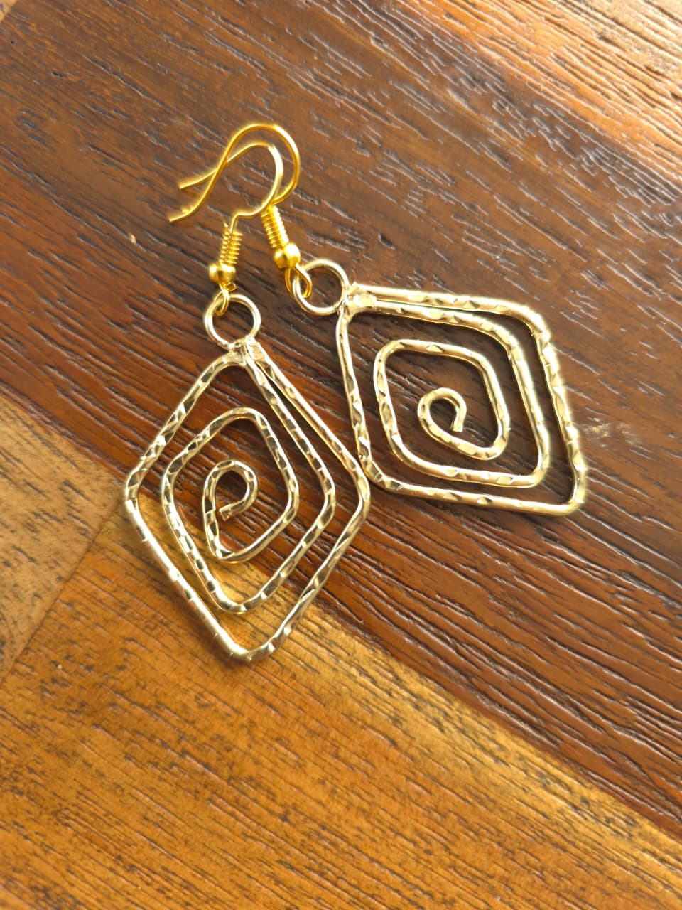 Elegant gold spiral earrings, handcrafted, featuring unique hammered design and secure hooks.