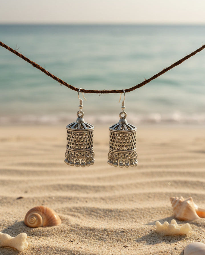 Silver jhumka earrings with intricate designs and dangling details, perfect for beach outings.