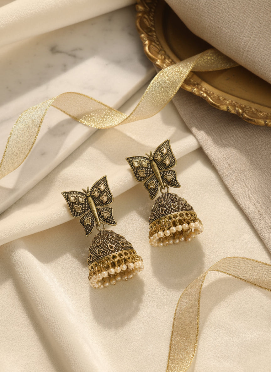 Vintage butterfly earrings with intricate design, gold-tone metal, and pearl accents, elegant statement piece.